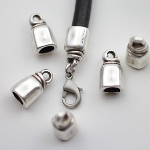 Può includere: Cappucci terminali in metallo color argento e chiusura a moschettone per la creazione di gioielli. I cappucci terminali hanno la forma di piccole campane e hanno una finitura liscia e lucida.