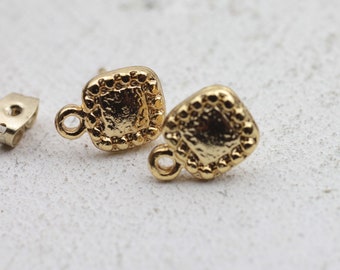 May include: A pair of gold-toned square earring studs with a textured border. The earrings have a small loop on the side for attaching to a post.