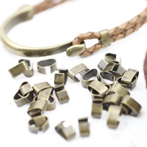 Peut inclure: Gros plan sur un tas de petites attaches m&eacute;talliques dor&eacute;es. Les attaches sont con&ccedil;ues pour &ecirc;tre utilis&eacute;es pour les bracelets en cuir ou d'autres bijoux.