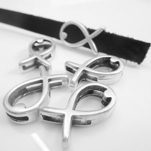 Puede incluir: Cinco abalorios de metal plateados en forma de pez con un corazón en su interior. Los abalorios están diseñados para ser usados en una pulsera o collar.