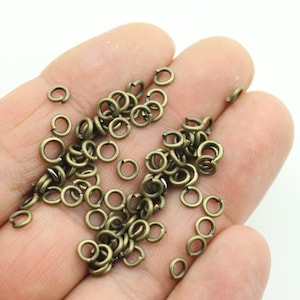 Könnte beinhalten: Ein großer Haufen kleiner, antiker goldener Sprungringe. Die Ringe sind alle gleich groß und aus Metall.