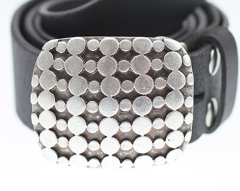May include: A black leather belt with a silver buckle. The buckle is decorated with a pattern of small circles.
