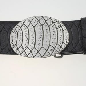 May include: A black leather belt with a silver oval buckle featuring a textured snake skin design.