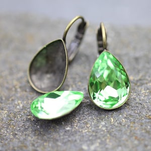 Puede incluir: Un par de pendientes de bronce antiguo con piedras de cristal verdes en forma de lágrima.