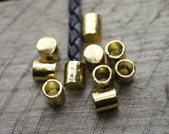 May include: A close-up of ten gold-colored metal beads, some with a textured surface. The beads are arranged on a wooden surface.