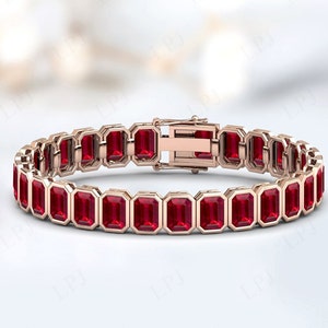 May include: A rose gold bracelet featuring a row of red emerald-cut gemstones. The bracelet has a clasp fastening.