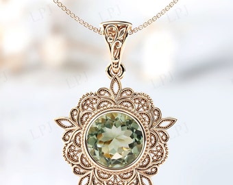 Può includere: Una collana con ciondolo in oro con una pietra preziosa verde incastonata in un design a filigrana.