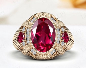 May include: A gold-toned ring featuring a large, oval-cut ruby as the centerpiece. The ring is adorned with smaller rubies and clear gemstones, set within an ornate, textured design. The ring's setting has intricate details.