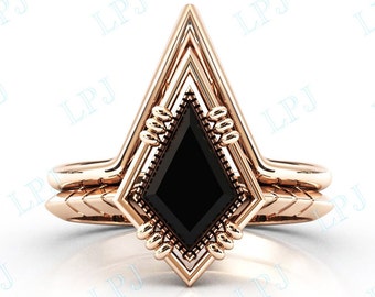 May include: A rose gold engagement ring with a black diamond set in a geometric, arrow-shaped design.