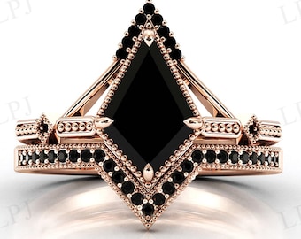 May include: A rose gold engagement ring set with a black square-shaped gemstone. The ring features a geometric design with black diamonds around the center stone and band.