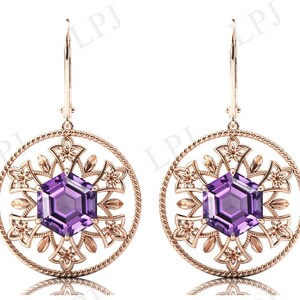 May include: A pair of rose gold earrings with a delicate floral design and a large purple amethyst gemstone in the center of each earring.