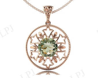 Può includere: Una collana con ciondolo in oro con una pietra preziosa verde rotonda incastonata in un delicato design a filigrana.