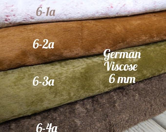 Könnte beinhalten: Vier Stoffproben übereinander gestapelt. Die oberste Probe ist weiß mit einem rosa Muster. Die zweite Probe ist braun. Die dritte Probe ist grün. Die unterste Probe ist braun. Der Text "German Viscose 6 mm" ist auf die Stoffproben gedruckt.