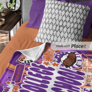 Peut inclure: Une couverture violette et blanche sur le th&egrave;me du coll&egrave;ge avec du texte et des graphiques, dont des &eacute;toiles et un dessin de mascotte. La couverture est sur un lit avec un oreiller blanc &agrave; motifs et des draps violets.