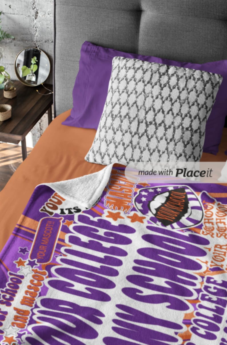 Peut inclure: Une couverture violette et blanche sur le th&egrave;me du coll&egrave;ge avec du texte et des graphiques, dont des &eacute;toiles et un dessin de mascotte. La couverture est sur un lit avec un oreiller blanc &agrave; motifs et des draps violets.