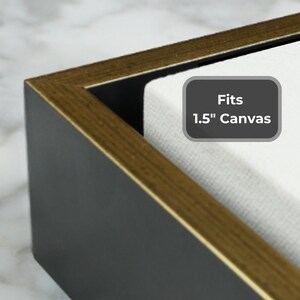 May include: Close-up of a black canvas frame with a gold-colored trim. The frame is designed to fit a 1.5-inch canvas. The text "Fits 1.5" Canvas" is displayed on a gray label.