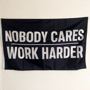 May include: Black flag with white text that reads "Nobody Cares Work Harder".