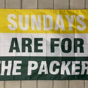 May include: A rectangular flag with three horizontal stripes in yellow, white, and green. The flag displays the text "SUNDAYS ARE FOR THE PACKERS" in large, bold, white letters. The flag has grommets for hanging.