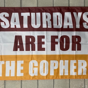 Peut inclure: Drapeau rectangulaire avec le texte "SATURDAYS ARE FOR THE GOPHERS" en lettres blanches. Le drapeau est divisé en trois sections horizontales : bordeaux, blanc et or. Le drapeau a des œillets pour l'accrocher.