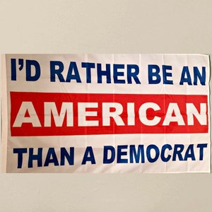 May include: A white flag with blue and red lettering that reads "I'd rather be an American than a Democrat".