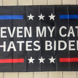 May include: Black flag with red and blue stripes and white stars. The flag says "Even my cat hates Biden".