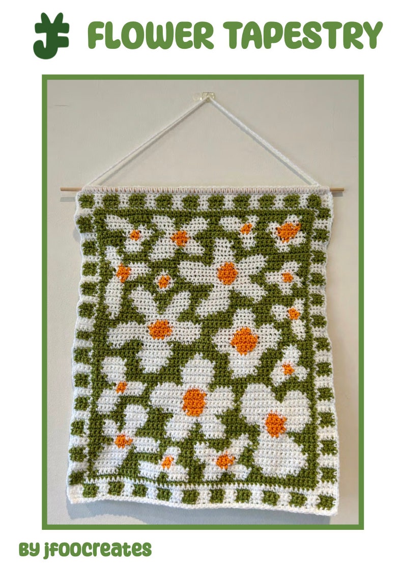 Puede incluir: Un tapiz de pared tejido a crochet con un patr&oacute;n de margarita en blanco, verde y naranja. El tapiz est&aacute; colgado en una pared blanca con una varilla de madera.