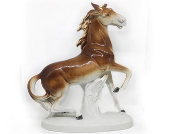 May include: A brown porcelain horse figurine standing on its hind legs with its front legs raised. The horse has a white base and a flowing mane.