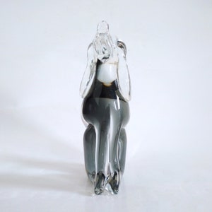 Pu&ograve; includere: Scultura in vetro trasparente e grigio raffigurante un cane seduto, con grandi orecchie. La scultura ha una finitura liscia e lucida, su sfondo bianco. Il corpo del cane &egrave; di colore grigio scuro.