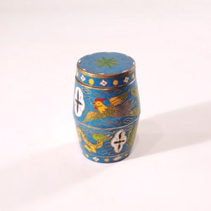 May include: A small, blue, cylindrical container with a lid, decorated with colourful birds and floral patterns. The container is made of metal and has a glossy finish.