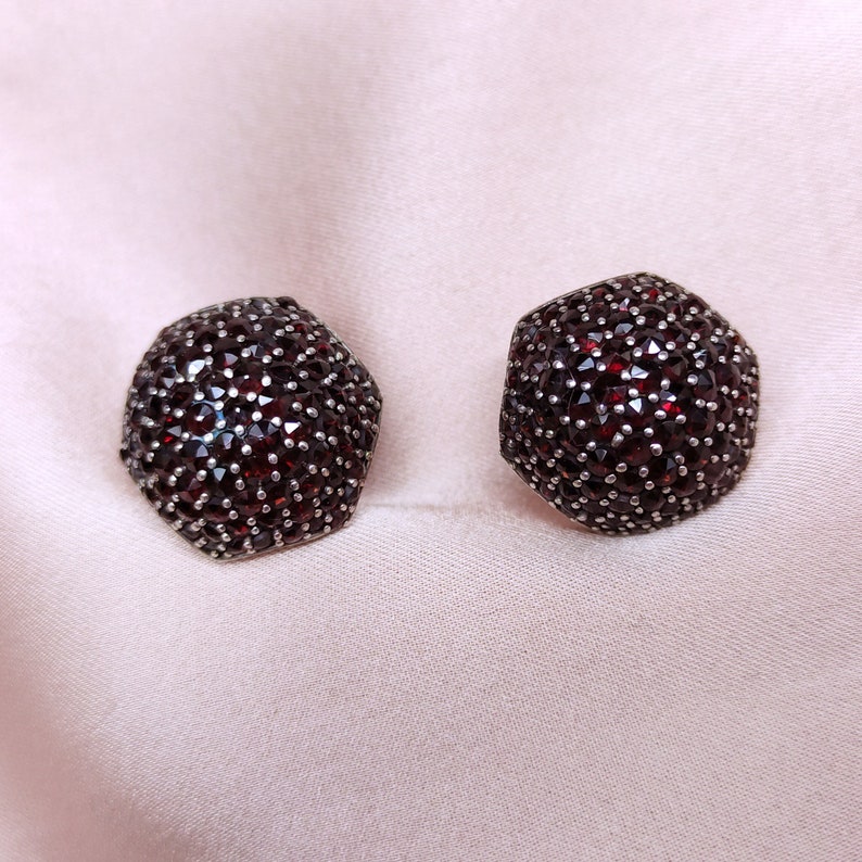 May include: A pair of silver earrings with red garnet stones set in a hexagonal shape.