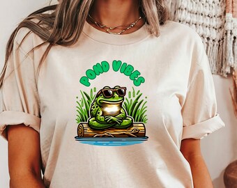 May include: A white t-shirt with a green frog wearing sunglasses and sitting on a log. The text "POND VIBES" is written in green letters around the frog.