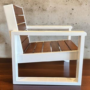 May include: A small, white wooden chair with a slatted seat and backrest made of brown wood. The chair has a simple, modern design and is suitable for indoor or outdoor use.