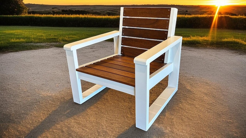 May include: A modern outdoor chair with a white frame and brown wooden seat and back. The chair has a slatted back and seat, and armrests. The chair is set against a backdrop of green grass and a sunset.