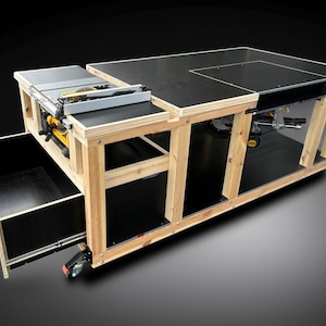 K&ouml;nnte beinhalten: Eine Werkbank aus Holz mit schwarzer Tischplatte und eingebauter Tischkreiss&auml;ge. Die Werkbank hat eine Schublade und ist f&uuml;r Mobilit&auml;t auf R&auml;dern montiert. Der Rahmen ist aus Naturholz.