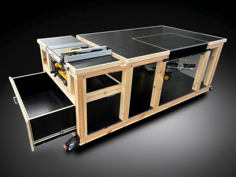 K&ouml;nnte beinhalten: Eine Werkbank aus Holz mit schwarzer Tischplatte und eingebauter Tischkreiss&auml;ge. Die Werkbank hat eine Schublade und ist f&uuml;r Mobilit&auml;t auf R&auml;dern montiert. Der Rahmen ist aus Naturholz.