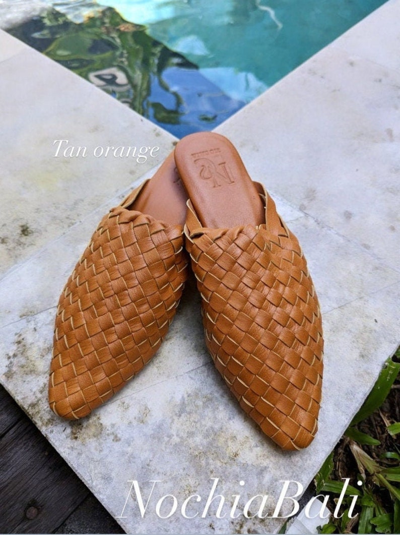 K&ouml;nnte beinhalten: Tan-orangefarbene geflochtene Leder-Mules mit spitzer Zehenpartie. Die Schuhe haben ein schlichtes Design und sind aus hochwertigem Leder gefertigt. Der Markenname "N" ist auf der Oberseite des Schuhs gepr&auml;gt.