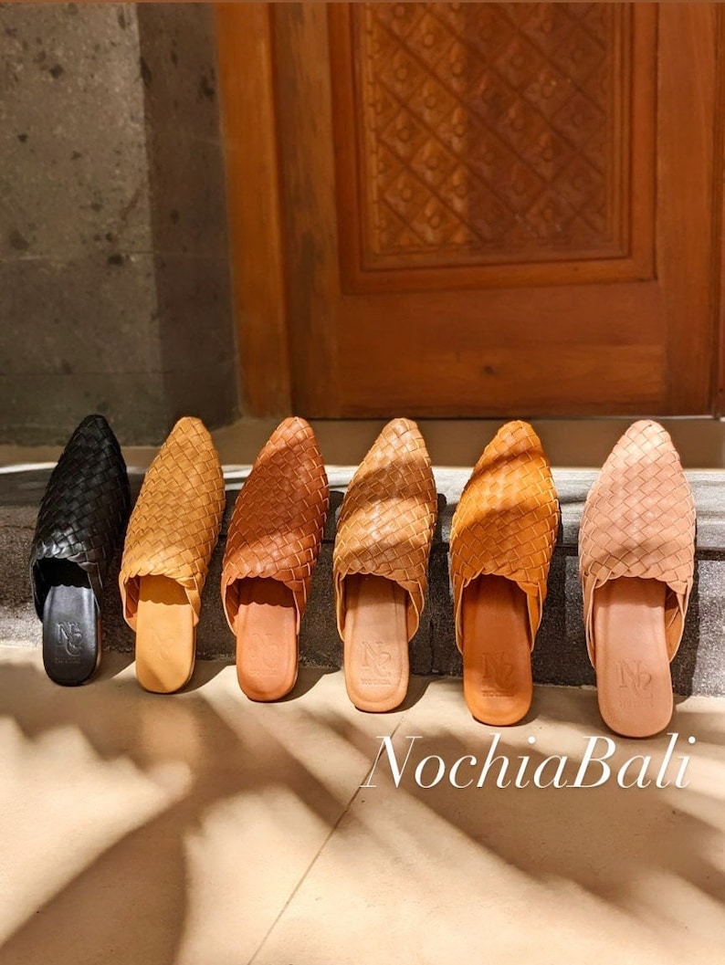 K&ouml;nnte beinhalten: Sechs Paar geflochtene Ledersandalen in verschiedenen Braunt&ouml;nen und Schwarz. Die Sandalen haben eine spitze Zehenpartie und eine flache Sohle. Die Sandalen sind in einer Reihe auf einer hellbraunen Oberfl&auml;che angeordnet. Der Text "NochlaBali" ist in der rechten unteren Ecke des Bildes sichtbar.