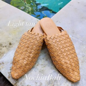 K&ouml;nnte beinhalten: Ein Paar hellbraune geflochtene Ledersandalen mit spitzer Zehenpartie. Die Sandalen befinden sich auf einer hellbraunen Oberfl&auml;che mit einem Pool im Hintergrund. Der Text "Light tan" und "NochlaBali" ist im Bild sichtbar.