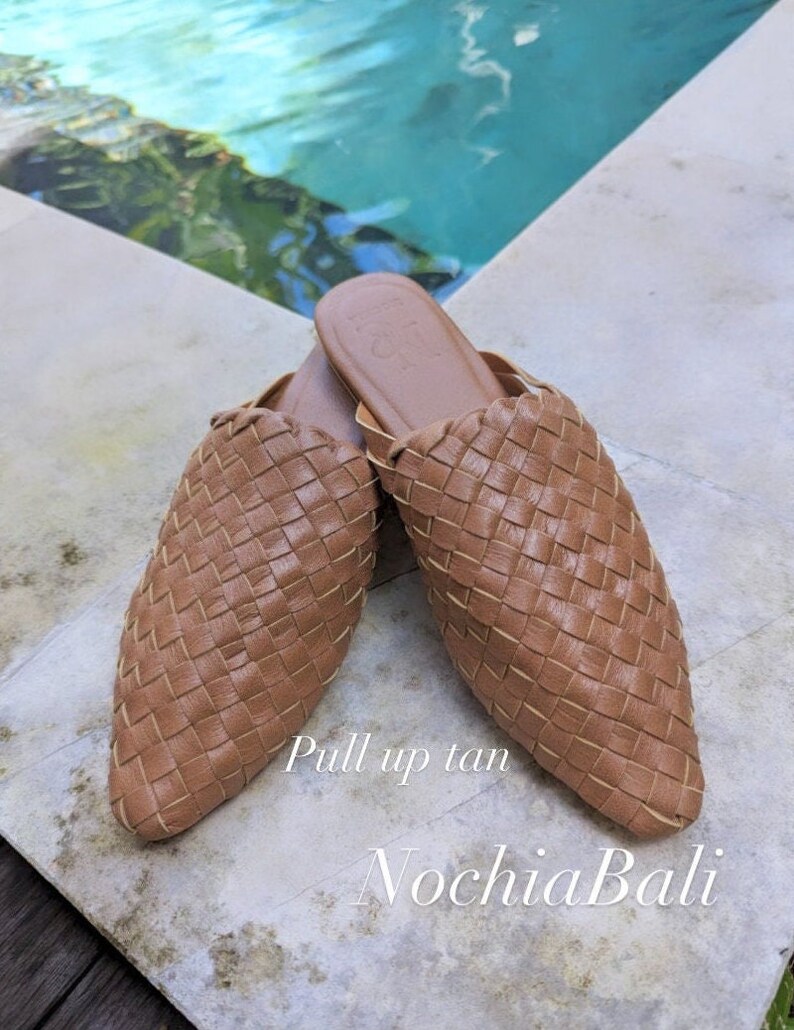 K&ouml;nnte beinhalten: Ein Paar geflochtene Lederslipper in Tan mit spitzer Zehenpartie. Die Schuhe befinden sich auf einer hellfarbigen Oberfl&auml;che mit dem Text "Pull up tan" und "NochlaBali" darunter.