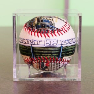 May include: A white baseball with red stitching and a colorful image of a baseball stadium. The baseball has the text "Truist Park" printed on it.