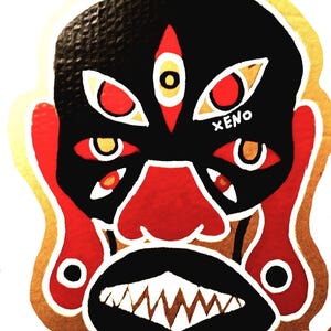 May include: A black and gold mask with red and yellow details. The mask has a large, open mouth with sharp teeth and a prominent nose. The eyes are large and round with white outlines. The word "XENO" is written in white on the mask.