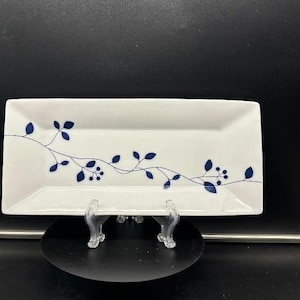 以下が含まれることがあります： 青い花柄の白い長方形のサービングプレート。デザインは、葉とベリーのあるつるを特徴としています。