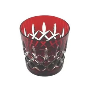 May include: A ruby red, cut crystal tumbler. The glass features a diamond pattern on the lower portion and vertical cuts near the rim. The tumbler is designed for beverages and has a classic, elegant appearance.