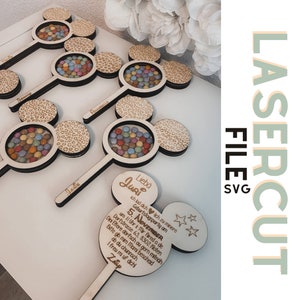 Könnte beinhalten: Lasergeschnittene Party-Gastgeschenke aus Holz in Form von Mickey Mouse-Köpfen, die jeweils bunte Süßigkeiten in einem transparenten Kreis enthalten. Einige Gastgeschenke sind mit Namen graviert. Das Design umfasst ein Leopardenmuster und den Text "LASERCUT FILE SVG".
