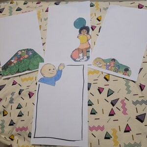 May include: Four blank white cards with a black border. The cards are arranged in a rectangle shape. The cards are on a white and yellow patterned surface. The cards are decorated with colourful illustrations of children playing with balloons.