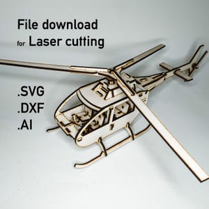 May include: A laser-cut wooden helicopter model with detailed design. The image includes the text "File download for Laser cutting" and file type options: .SVG, .DXF, and .AI. The model features a main rotor, tail rotor, and landing skids.