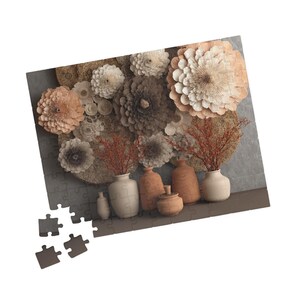 May include: A decorative wall art piece with paper flowers in cream, brown, and peach hues. Below, a collection of ceramic vases and pots in various sizes and shapes, with red-brown branches in some. A puzzle is in the foreground.