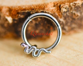 May include: Silver snake cartilage earring with a textured finish. The snake is curled around a silver hoop.