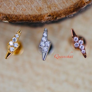 May include: Three lightning bolt shaped earrings with clear cubic zirconia stones. The earrings are in gold, silver, and rose gold.