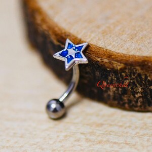 May include: A silver belly button ring with a blue and white enamel star charm.